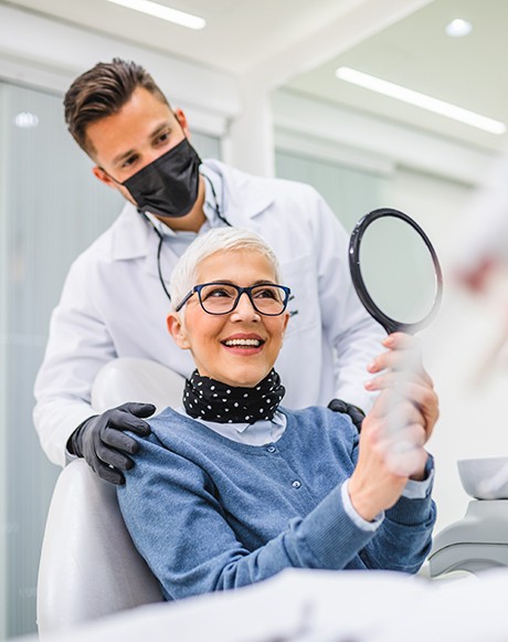 a dental implant patient holding a hand mirror