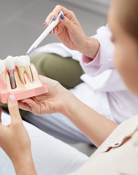 a patient holding a model of a dental implant